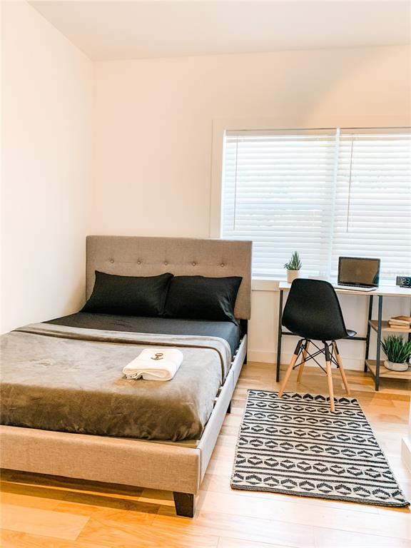 A bedroom features a gray upholstered bed, a desk with a laptop, and a patterned rug — 1619 9TH AVENUE N, ST PETERSBURG, FL