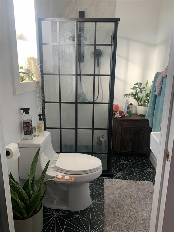 A bathroom features a black-framed glass shower, a toilet with a bidet, and patterned flooring — 1619 9TH AVENUE N, ST PETERSBURG, FL