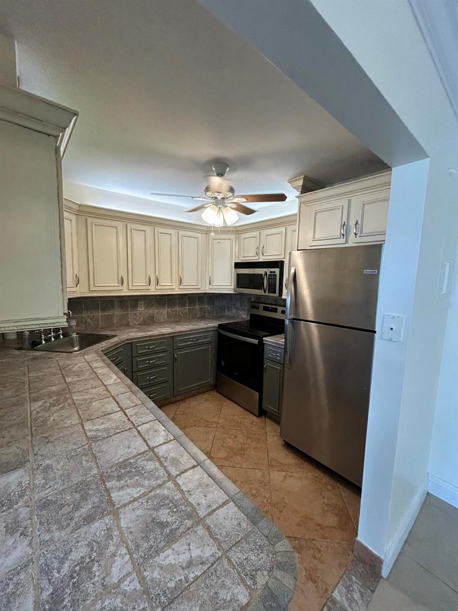 A kitchen features two-toned cabinetry, stainless steel appliances, and tiled countertops and flooring — 305 N Pompano Beach Boulevard # 205, Pompano Beach FL 33062, POMPANO BEACH, FL