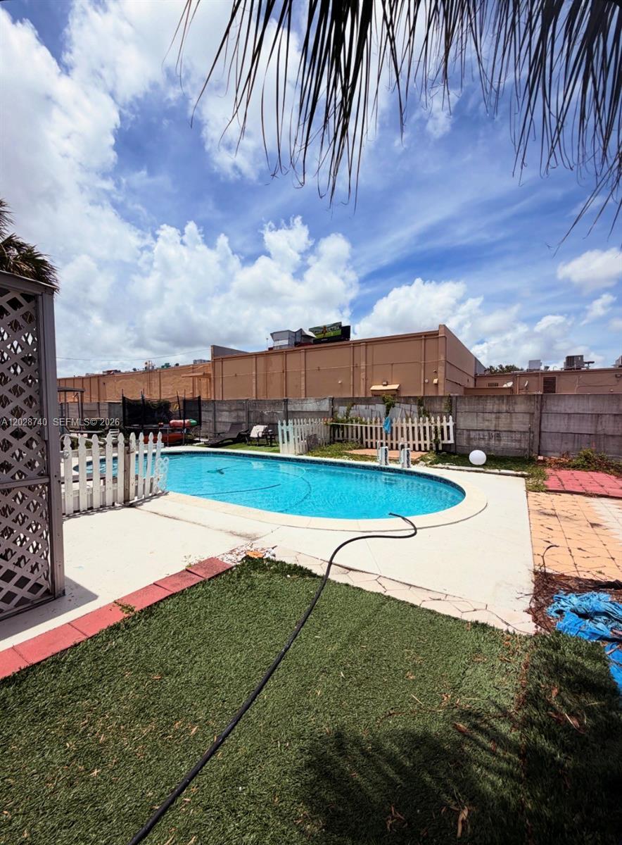 A backyard features a swimming pool, a white picket fence, and artificial turf — 1077 SW 2nd St # 2, Hallandale Beach FL 33009, HALLANDALE BEACH, FL