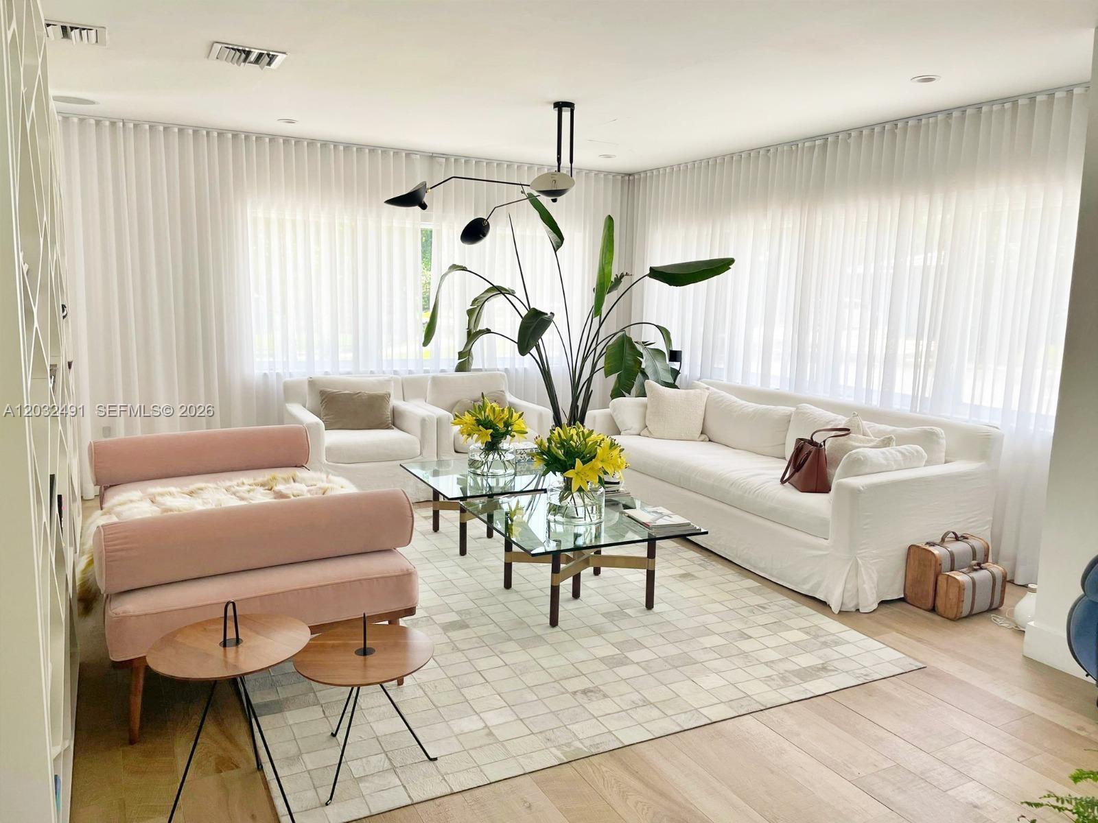 A bright living room features white sofas, a pink daybed, glass coffee tables, and sheer curtains — 290 E Shore Dr E # 290, Miami FL 33133, MIAMI, FL