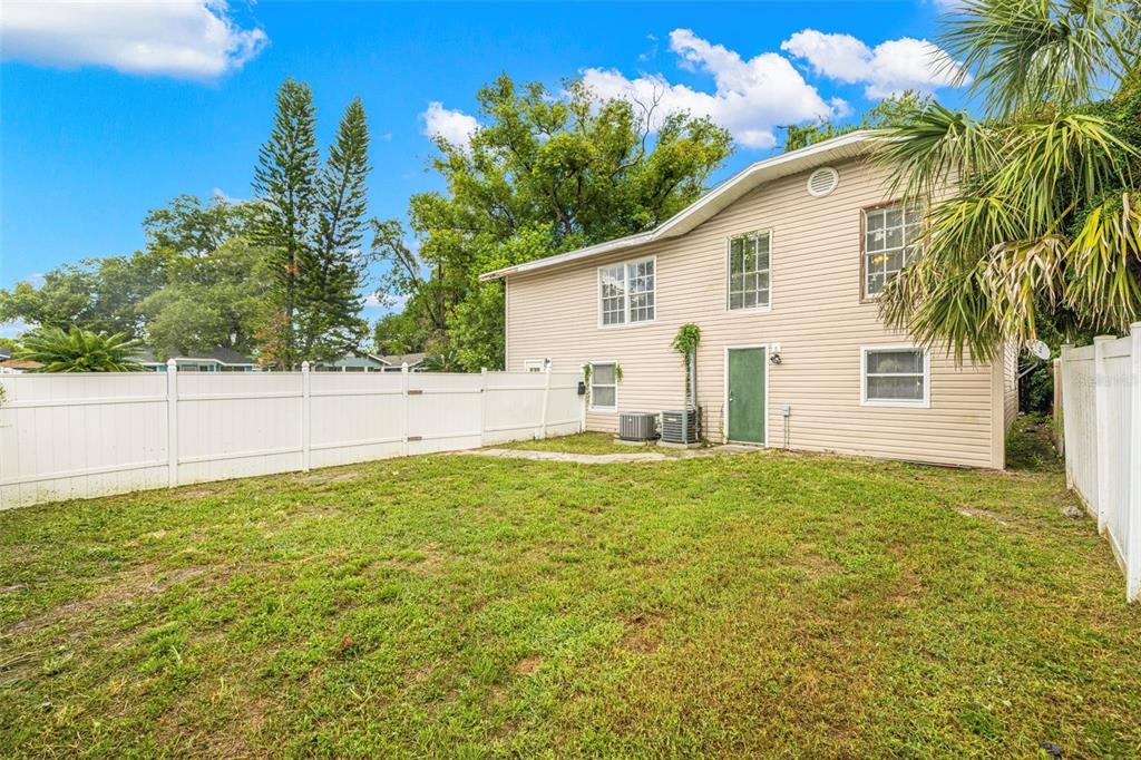 The exterior of a two-story beige house with a fenced backyard and green door — 305 E HANNA AVENUE, TAMPA, FL