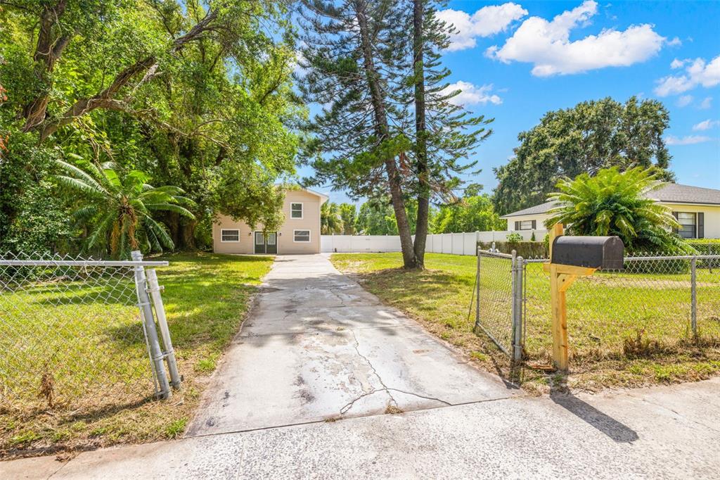 A concrete driveway leads to a two-story house behind a chain-link fence and mailbox — 305 E HANNA AVENUE, TAMPA, FL