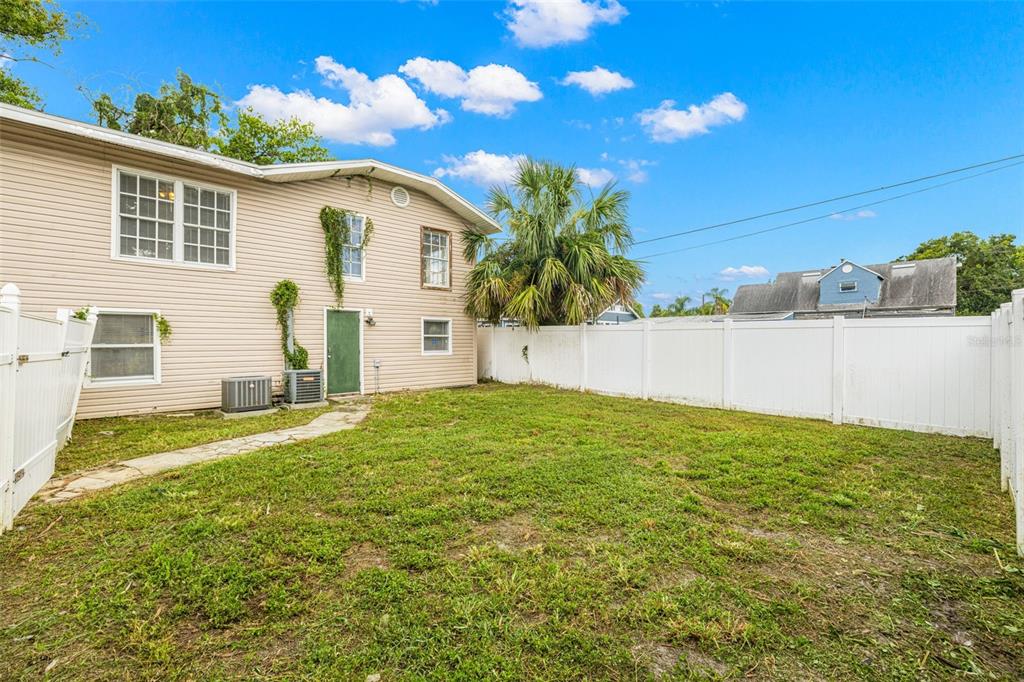 The exterior of a two-story house with beige siding and a fenced backyard — 305 E HANNA AVENUE, TAMPA, FL