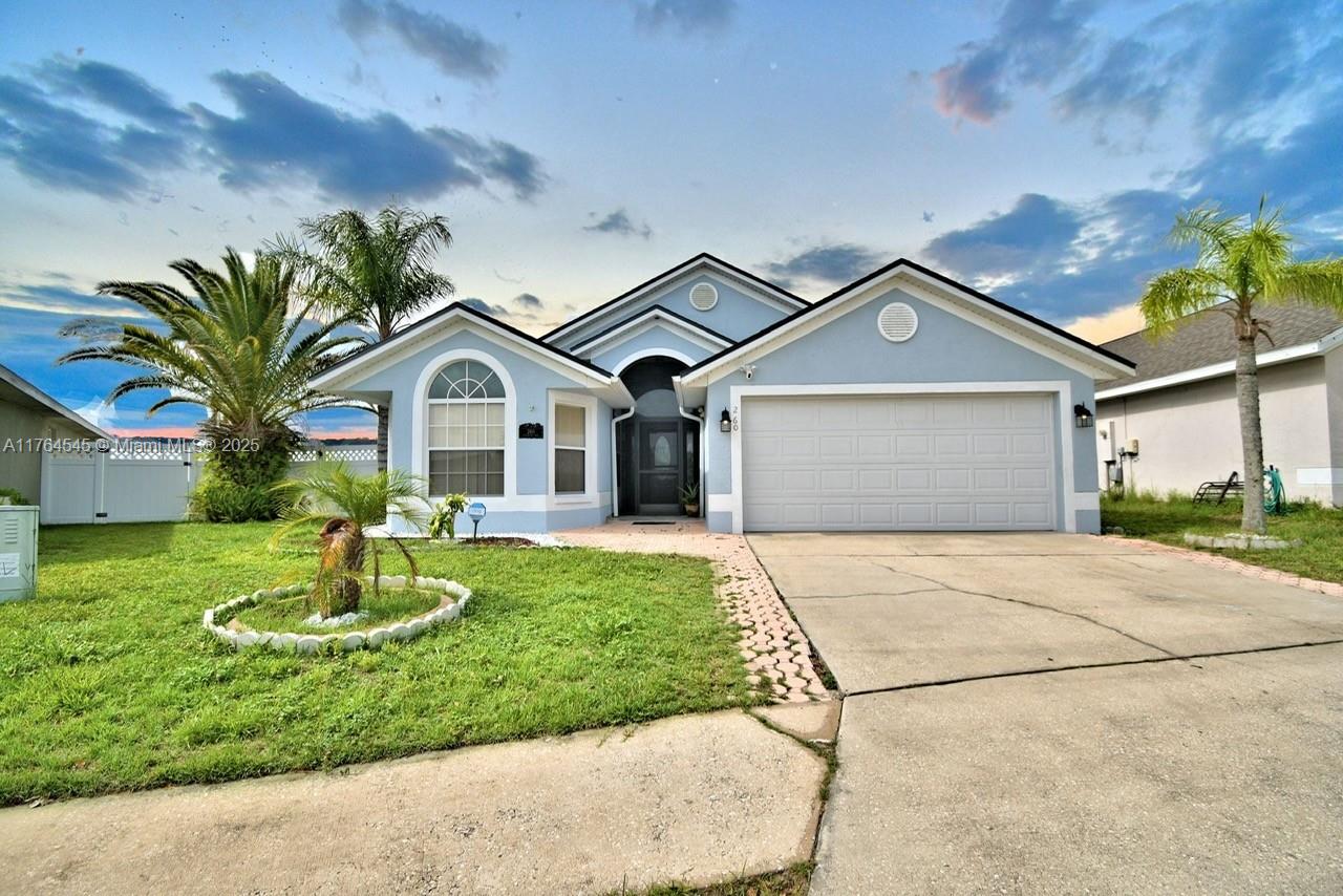 A single-story light blue house with a two-car garage and a front lawn — 260 CHESHIRE WAY, Davenport FL 33897, DAVENPORT, FL