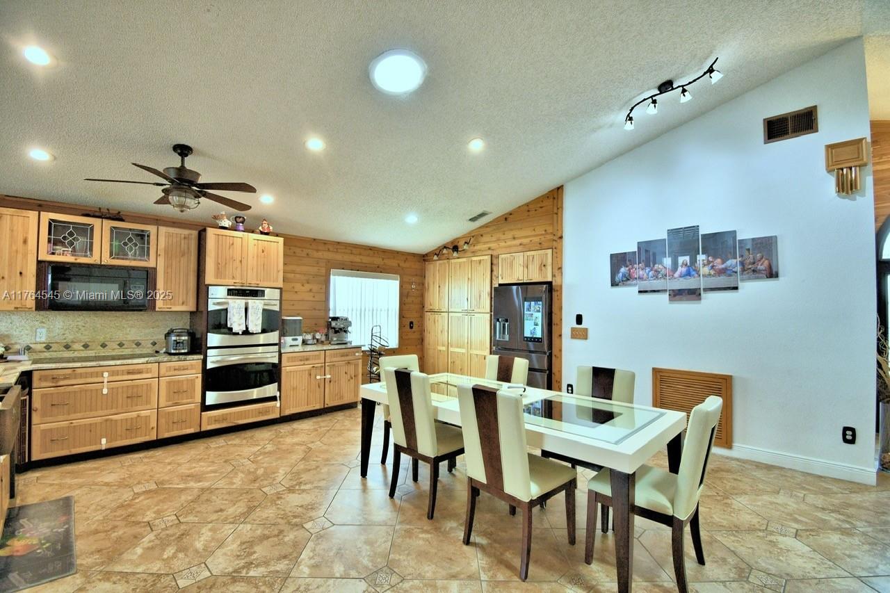 A kitchen and dining area features light wood cabinets, tile flooring, and vaulted ceilings — 260 CHESHIRE WAY, Davenport FL 33897, DAVENPORT, FL