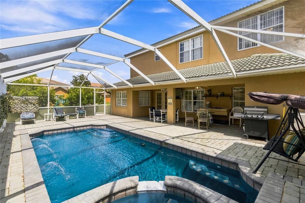 A screened-in backyard patio features a swimming pool, a hot tub, and outdoor furniture — 426 VISTA LOOP, DAVENPORT, FL