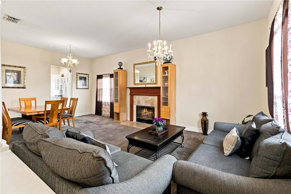 A living room with a fireplace, dining area, gray sofas, and two crystal chandeliers — 426 VISTA LOOP, DAVENPORT, FL