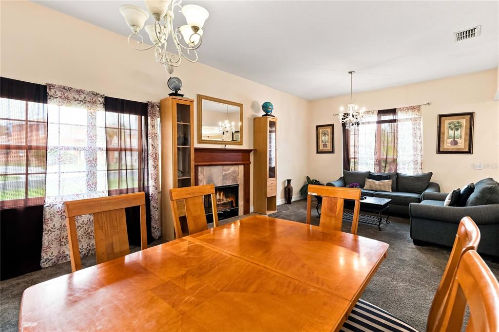 A dining area with a wooden table and chairs opens into a living room with carpet — 426 VISTA LOOP, DAVENPORT, FL