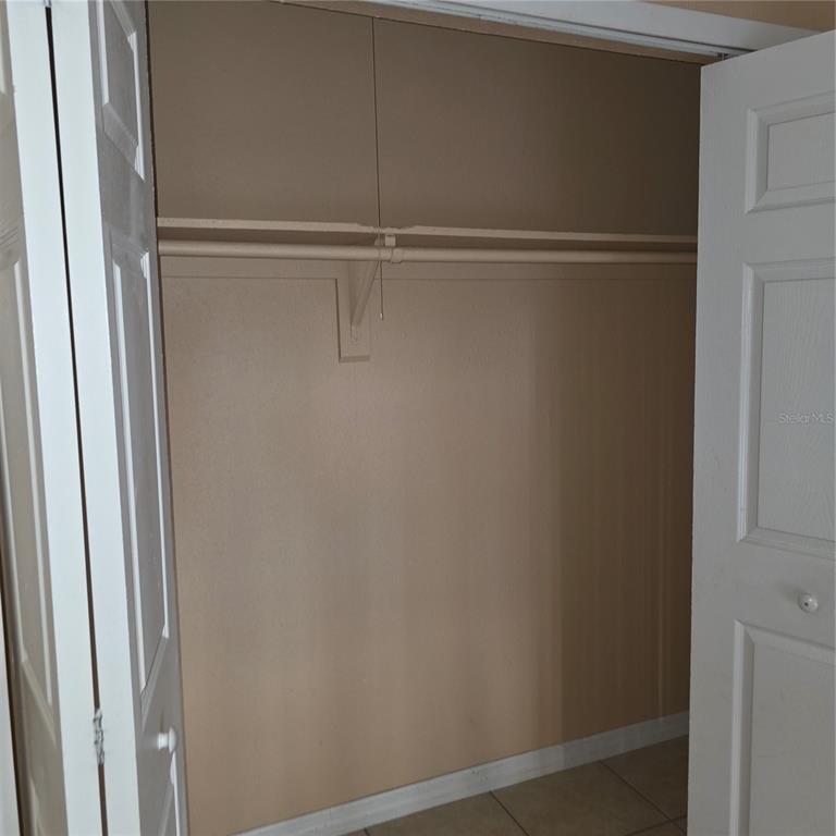 An open closet features a beige interior, a single shelf, and a hanging rod — 1707 MICHIGAN AVENUE UNIT D, KISSIMMEE, FL