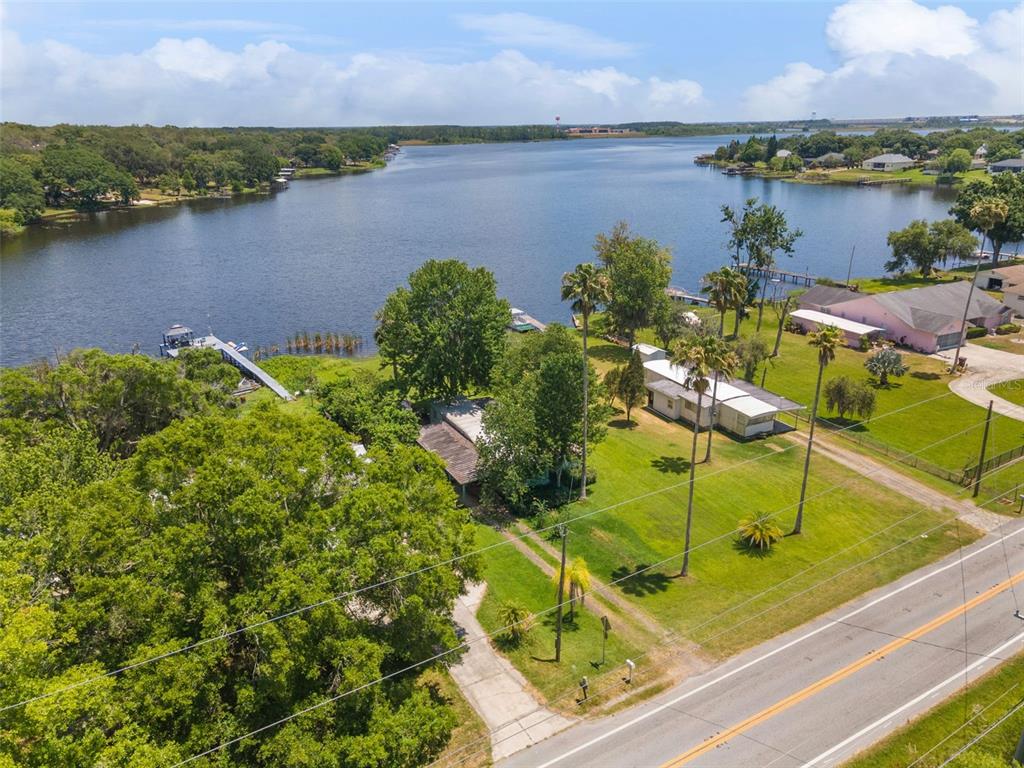 An aerial view shows a lakeside property with two houses, palm trees, and a private dock — 7570 BERKLEY ROAD, POLK CITY, FL