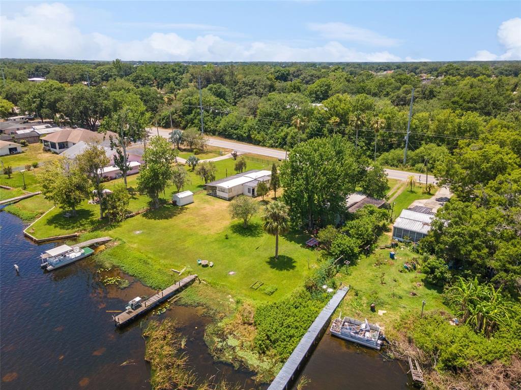 An aerial view shows a waterfront property with two houses, docks, and a grassy yard — 7570 BERKLEY ROAD, POLK CITY, FL