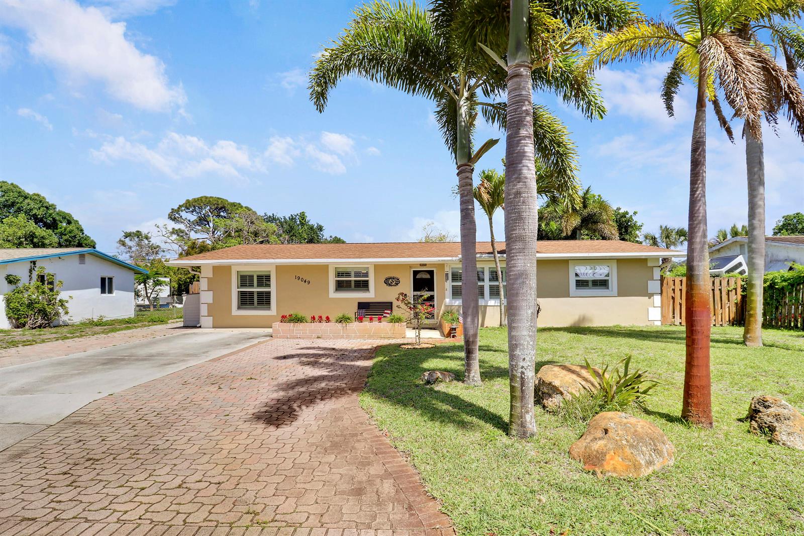 A one-story tan house with a brick driveway and palm trees in the front yard — 19049 SE Robert Drive, Jupiter FL 33469, JUPITER, FL