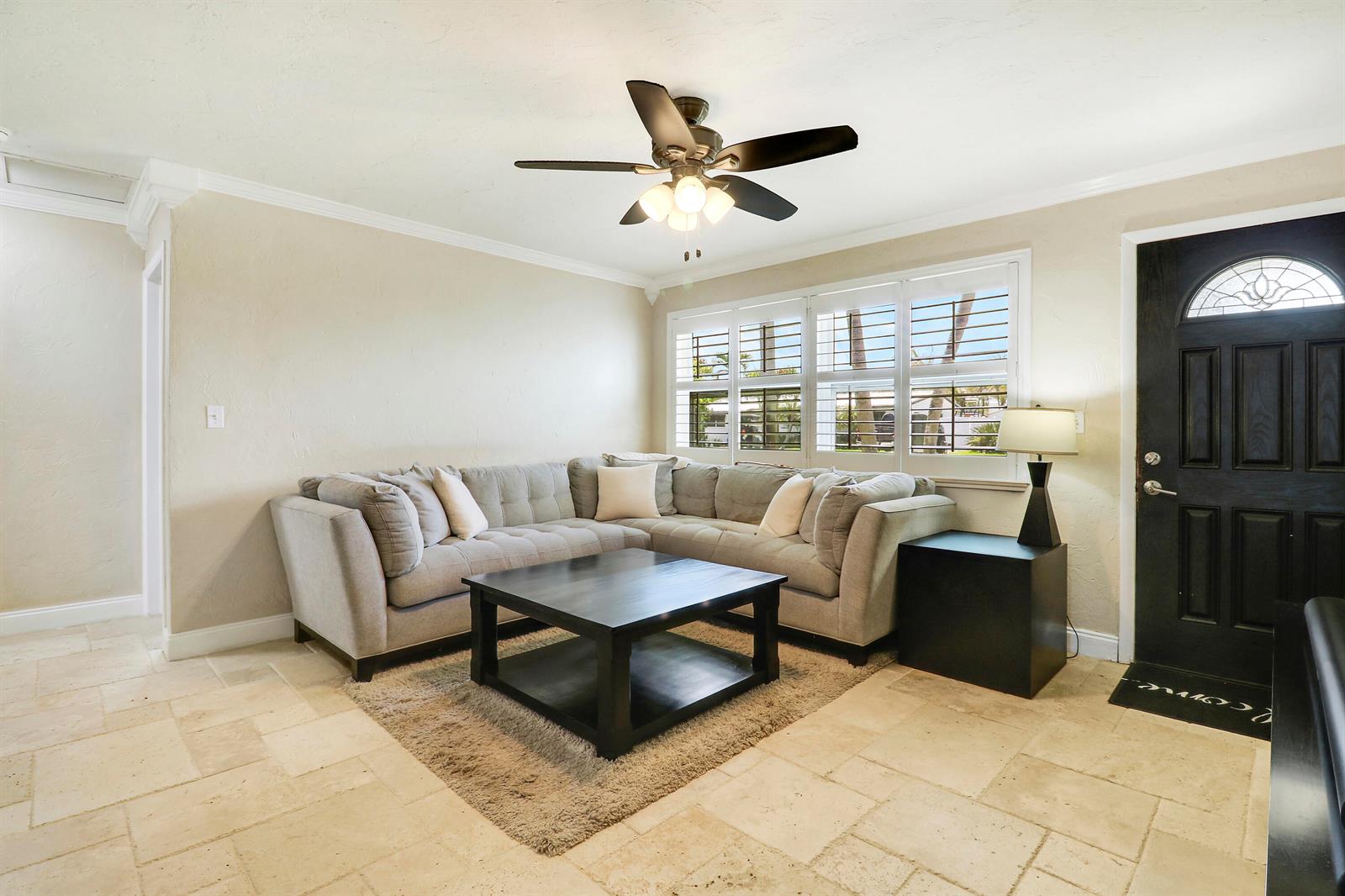 A living room features a grey sectional sofa, a dark coffee table, and tile flooring — 19049 SE Robert Drive, Jupiter FL 33469, JUPITER, FL