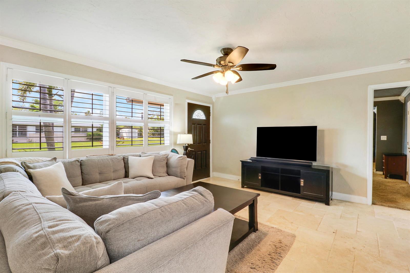 A living room features a gray sectional sofa, a television on a stand, and tile flooring — 19049 SE Robert Drive, Jupiter FL 33469, JUPITER, FL