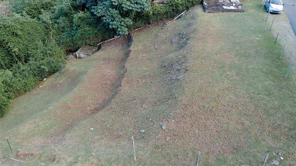 An aerial view shows a sloped, grassy vacant lot bordered by trees and a fence — 31 SAMUEL FELIX, VIEQUES, PR