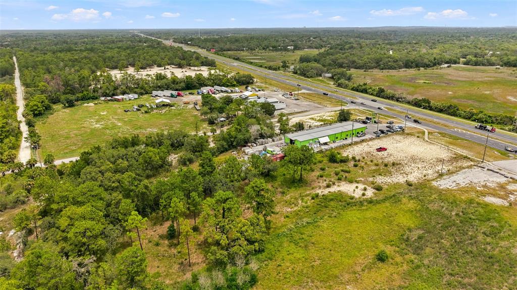 An aerial view shows a commercial property with a green building and parking near a highway — COMMERCIAL WAY, WEEKI WACHEE, FL