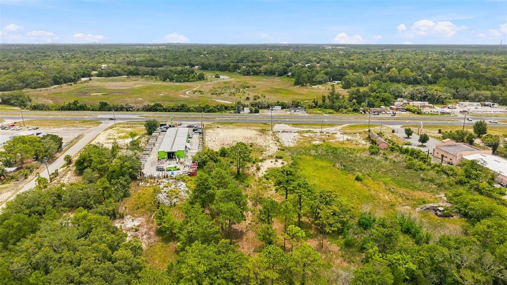 An aerial view shows a commercial building with a green roof next to vacant land — COMMERCIAL WAY, WEEKI WACHEE, FL