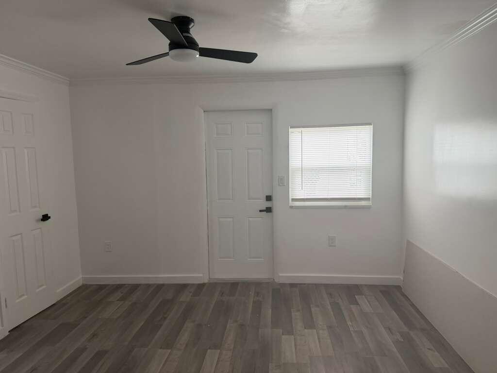 A room with white walls, gray wood-look flooring, a ceiling fan, a door, and a window — 2620 NE 7th Terrace, Pompano Beach FL 33064, POMPANO BEACH, FL