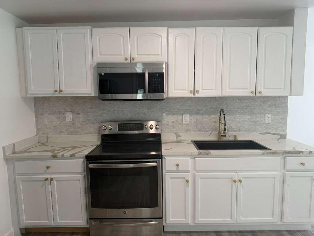 A kitchen features white cabinets, stainless steel appliances, a black sink, and marble-look countertops — 2620 NE 7th Terrace, Pompano Beach FL 33064, POMPANO BEACH, FL