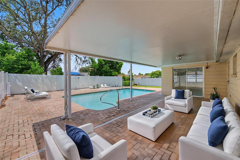 A living room features a gray sofa, two armchairs, a coffee table, and wood flooring — 9830 RAINBOW LANE, PORT RICHEY, FL