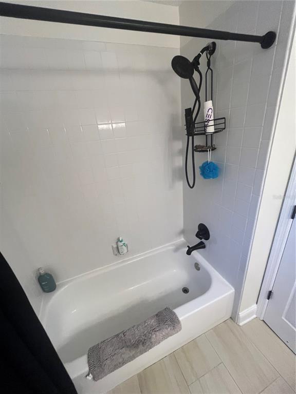 A white bathtub with a black showerhead and faucet is surrounded by white tiled walls — 1353 BLACK WILLOW TRAIL, ALTAMONTE SPRINGS, FL