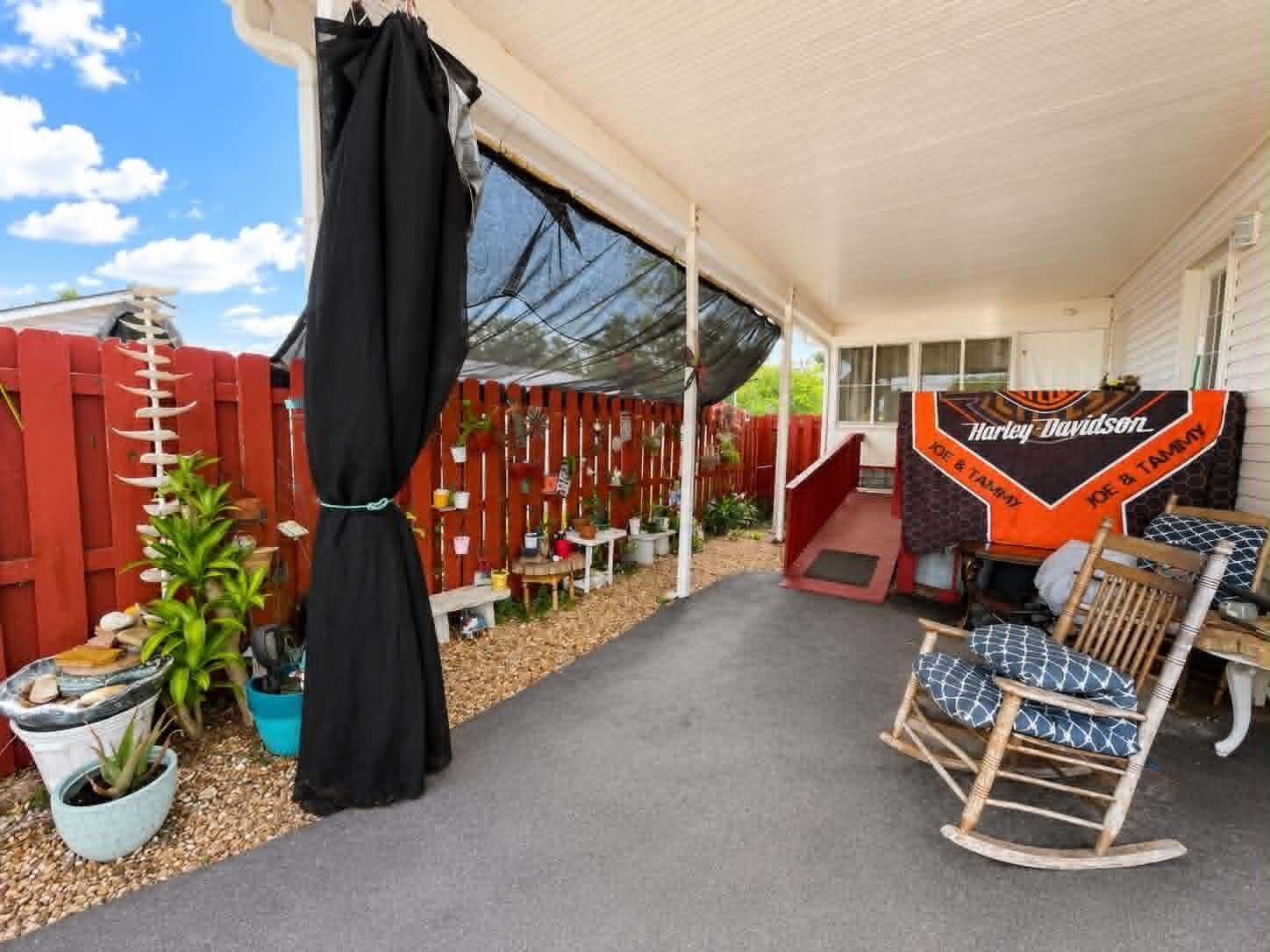 A covered patio features a red fence, a rocking chair, and a Harley-Davidson banner — 2908 SE 37th Avenue, Okeechobee FL 34974, OKEECHOBEE, FL