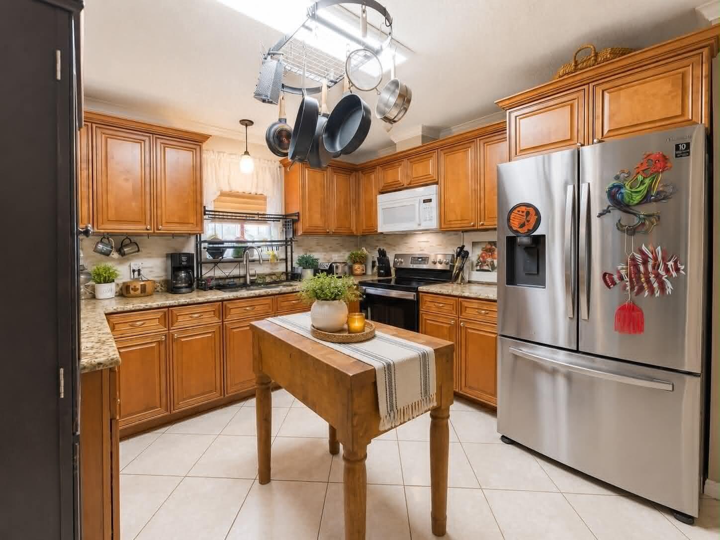 A kitchen features wood cabinets, stainless steel appliances, a central island, and a hanging pot rack — 2908 SE 37th Avenue, Okeechobee FL 34974, OKEECHOBEE, FL
