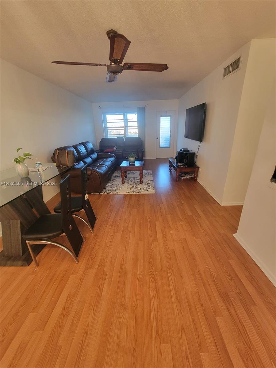 A living room features wood-look flooring, a brown leather sofa, and a ceiling fan — 1490 NW 43rd Ave # 308, Lauderhill FL 33313, LAUDERHILL, FL