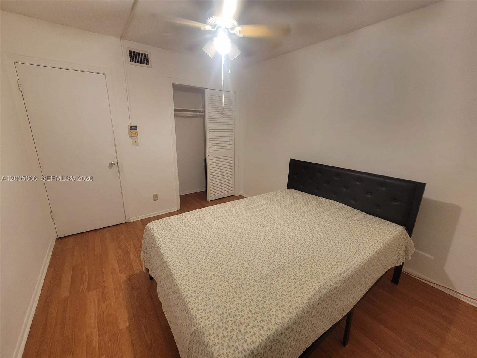 A bedroom features a bed with a black headboard, wood-look flooring, and a closet — 1490 NW 43rd Ave # 308, Lauderhill FL 33313, LAUDERHILL, FL