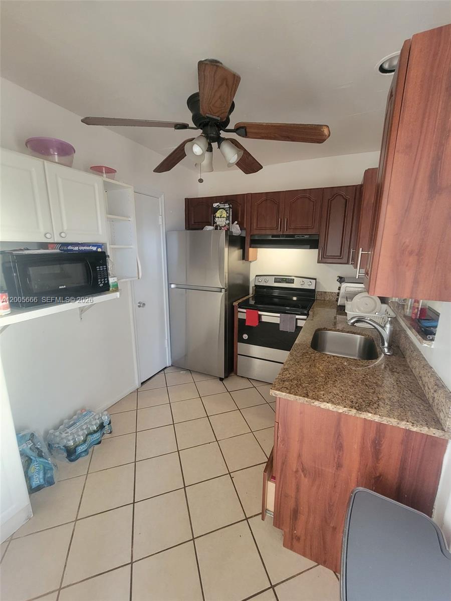 A kitchen features dark wood cabinets, granite countertops, stainless steel appliances, and tile flooring — 1490 NW 43rd Ave # 308, Lauderhill FL 33313, LAUDERHILL, FL