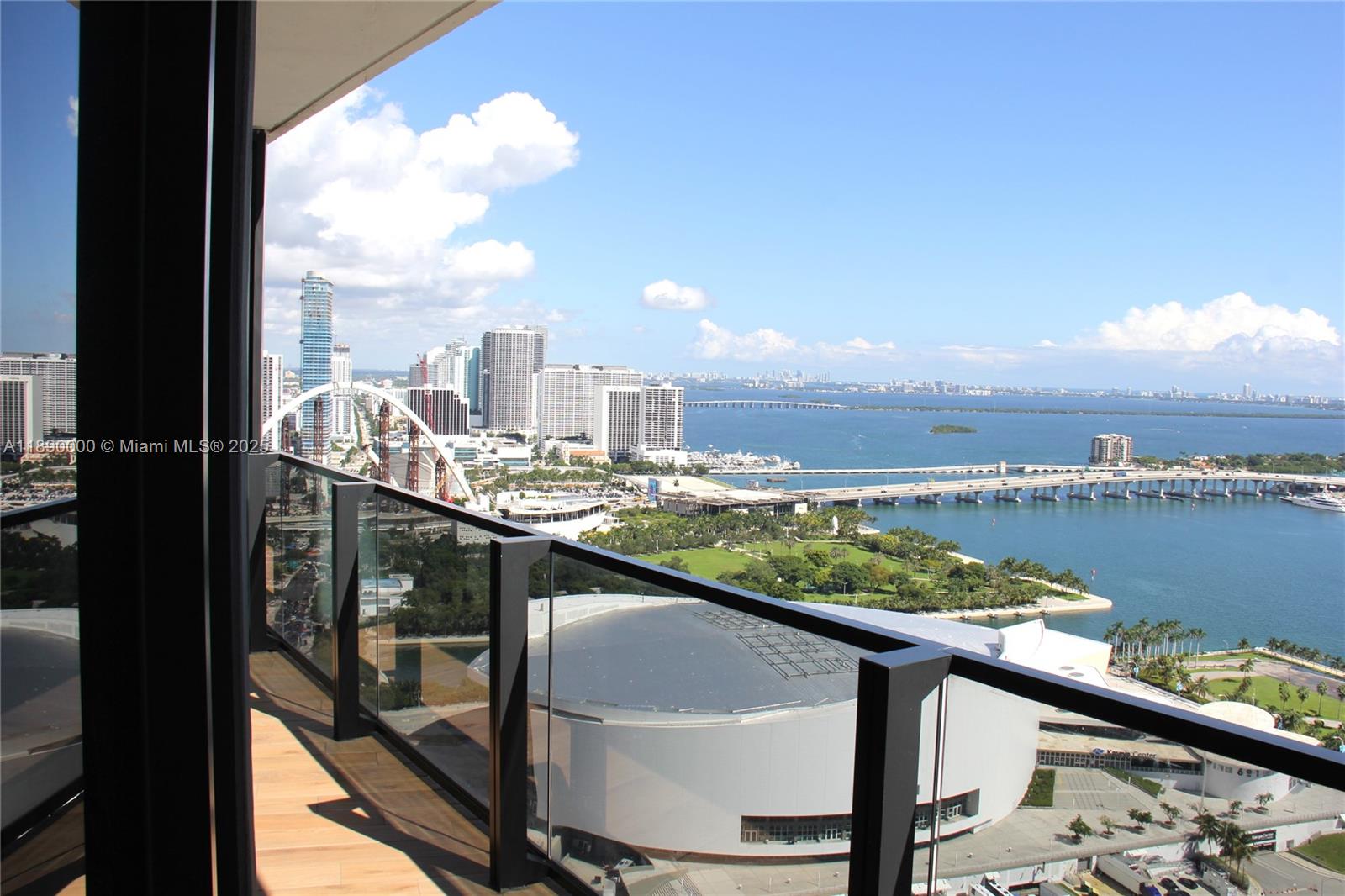 A balcony with glass railings overlooks a city skyline, a stadium, and the bay — 398 NE 5th St # 3310, Miami FL 33132, MIAMI, FL