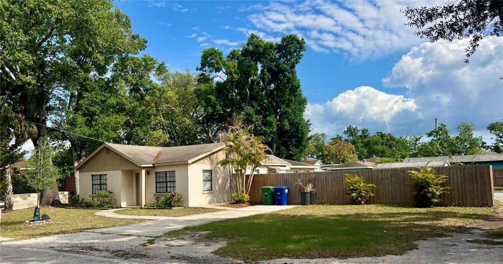 A single-story house with a tan exterior, a concrete driveway, and a wooden privacy fence — 3110 W IVY STREET, TAMPA, FL