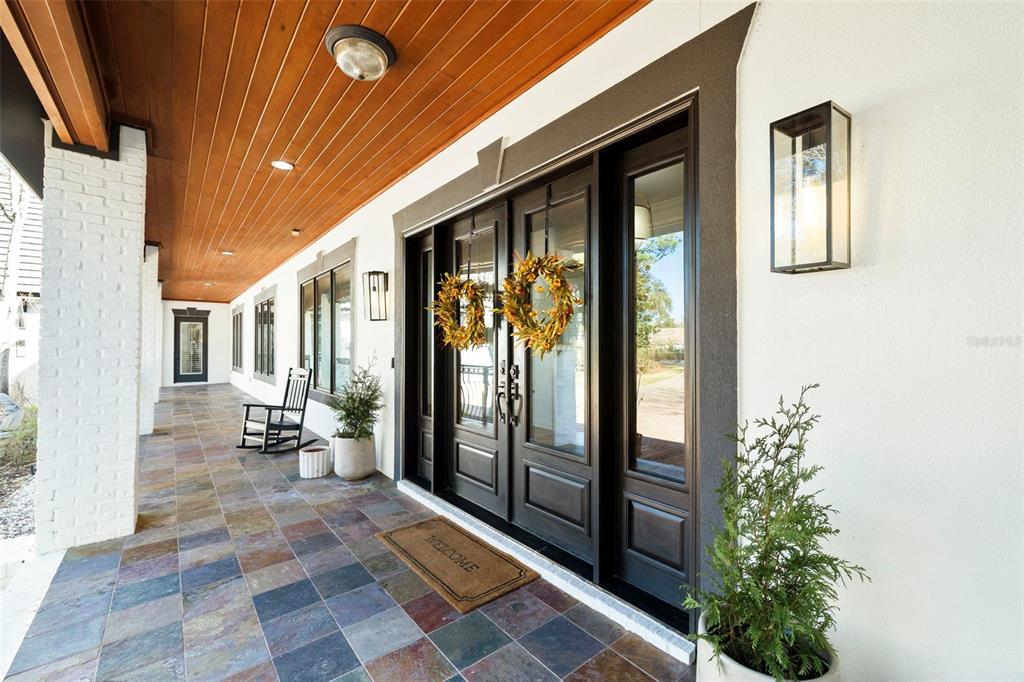 A covered porch features slate tile flooring, a wood-paneled ceiling, and dark-framed double front doors — 410 WINDJAMMER COURT, DESTIN, FL