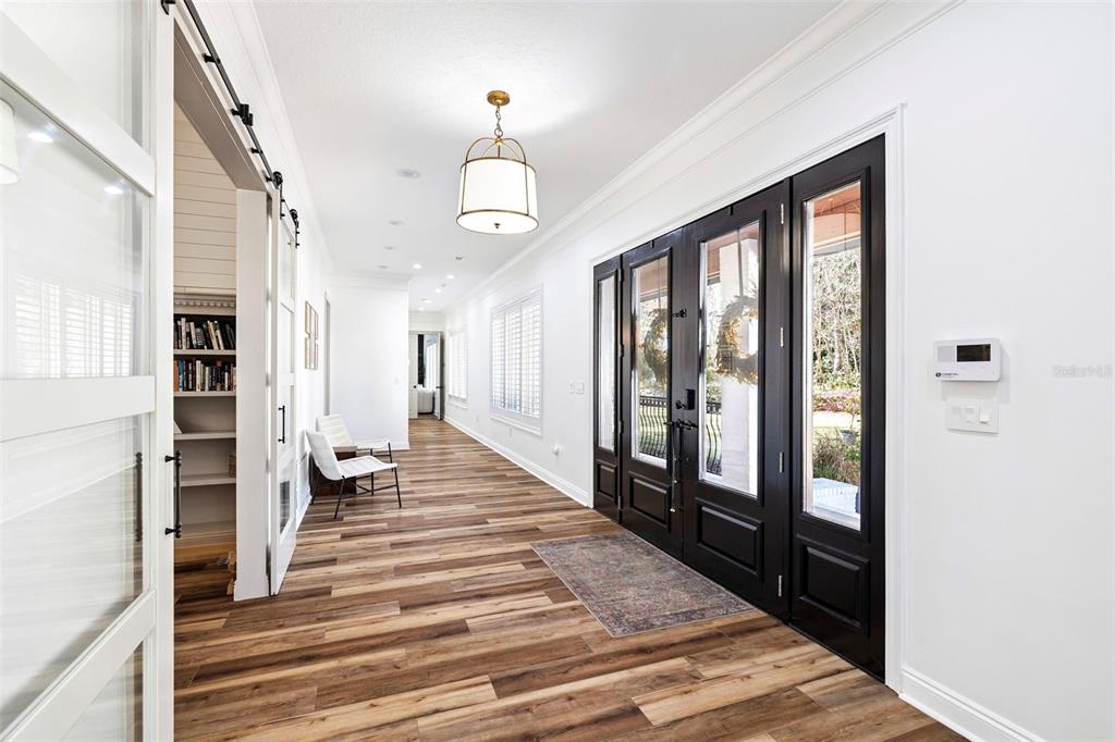 A bright entryway with wood-look flooring, a pendant light, and black double doors — 410 WINDJAMMER COURT, DESTIN, FL