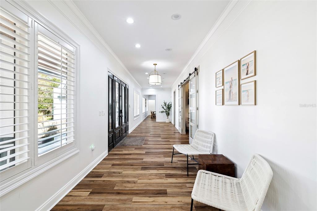 A long hallway features wood-look flooring, white walls, a pendant light, and two white chairs — 410 WINDJAMMER COURT, DESTIN, FL