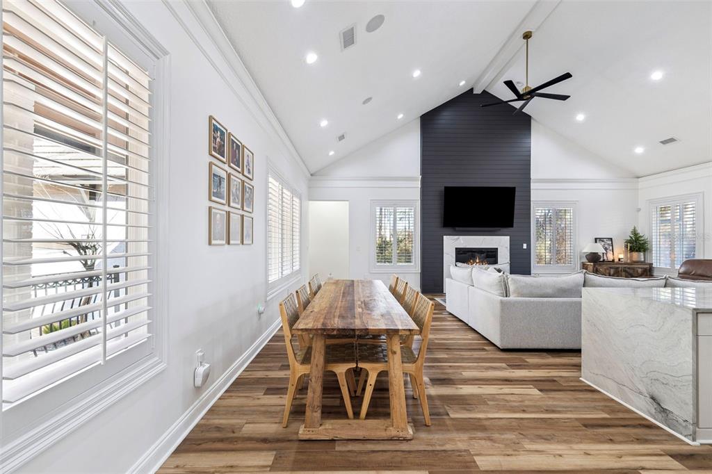 A dining area with a wooden table sits in an open-concept living space with vaulted ceilings — 410 WINDJAMMER COURT, DESTIN, FL