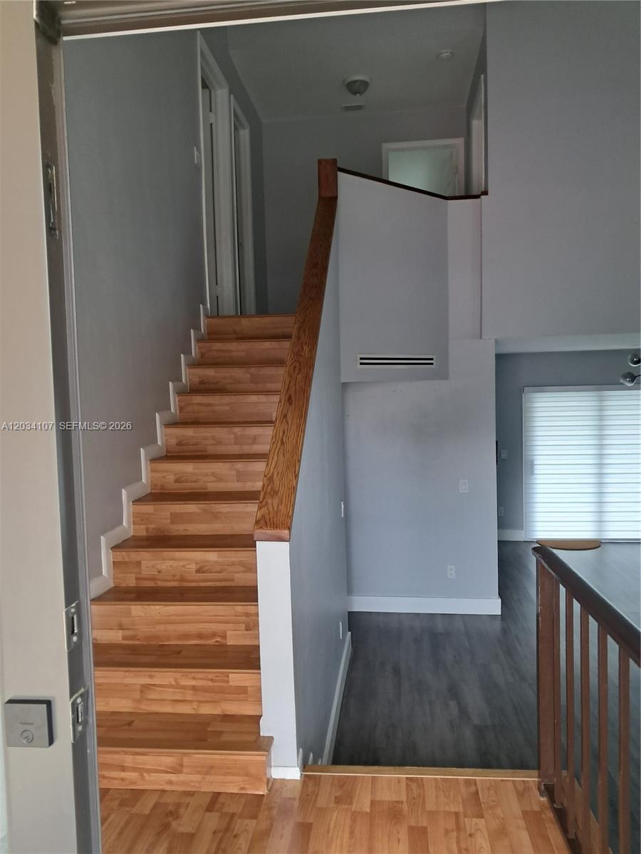 A staircase with wooden treads and a wooden handrail leads to an upper level — MIAMI, FL