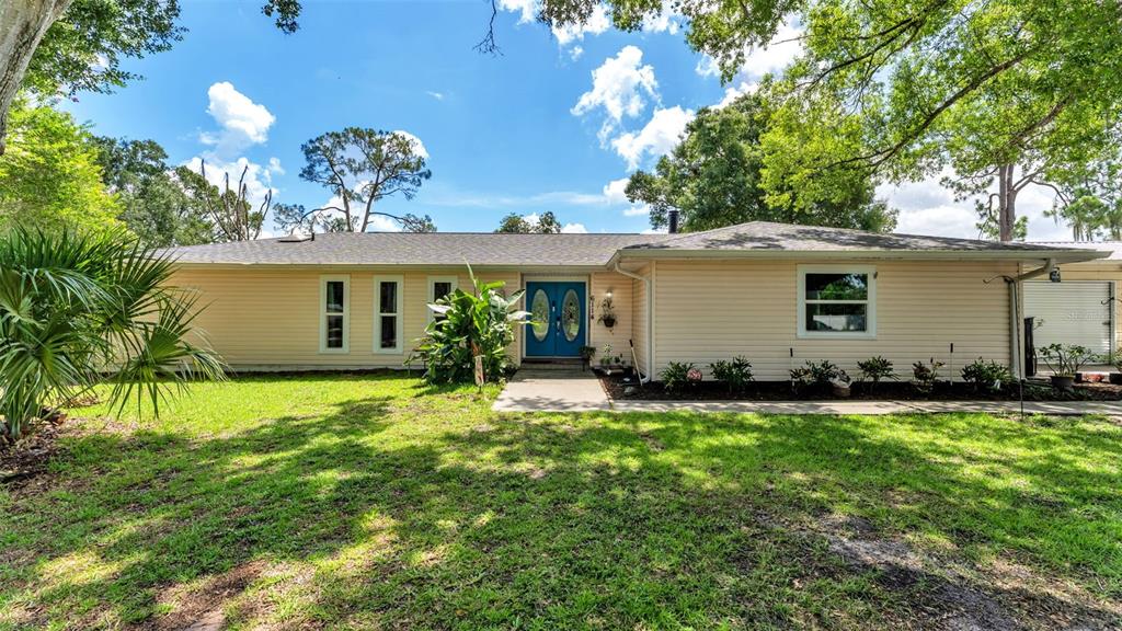 A single-story house with light-colored siding, a blue double front door, and a grassy yard — 6114 WENDEL WAY, LAKELAND, FL