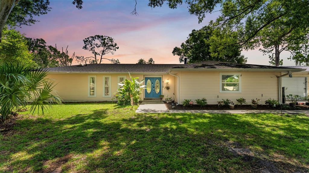 A single-story house with light yellow siding, a blue double front door, and a lawn — 6114 WENDEL WAY, LAKELAND, FL