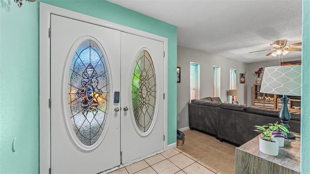 A white double front door with oval glass inserts opens into a living room area — 6114 WENDEL WAY, LAKELAND, FL