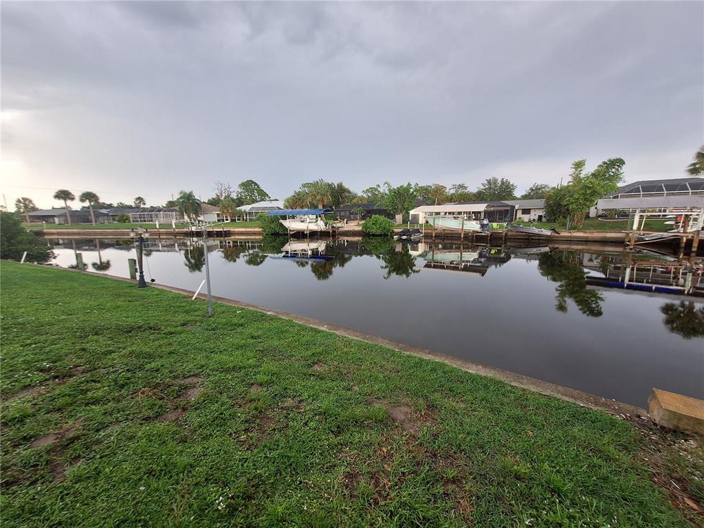 A grassy lawn overlooks a canal with several docked boats and houses in the background — 4050 YUCATAN CIRCLE, PORT CHARLOTTE, FL