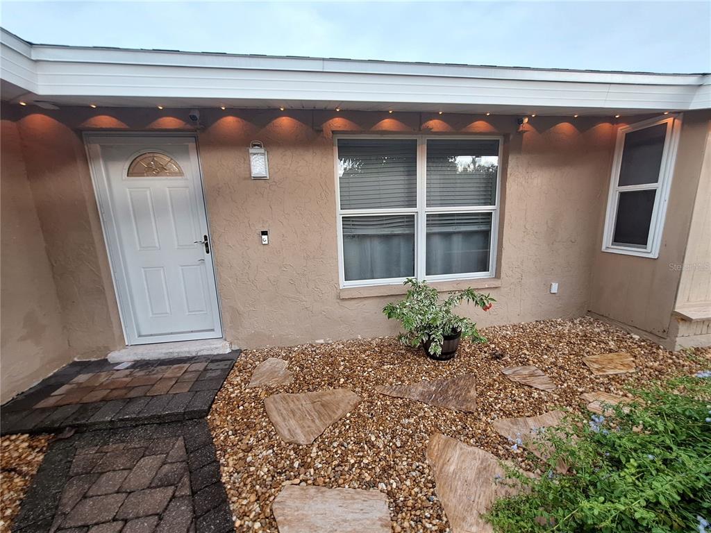 The exterior of a house features a white front door, a window, and a gravel yard — 4050 YUCATAN CIRCLE, PORT CHARLOTTE, FL