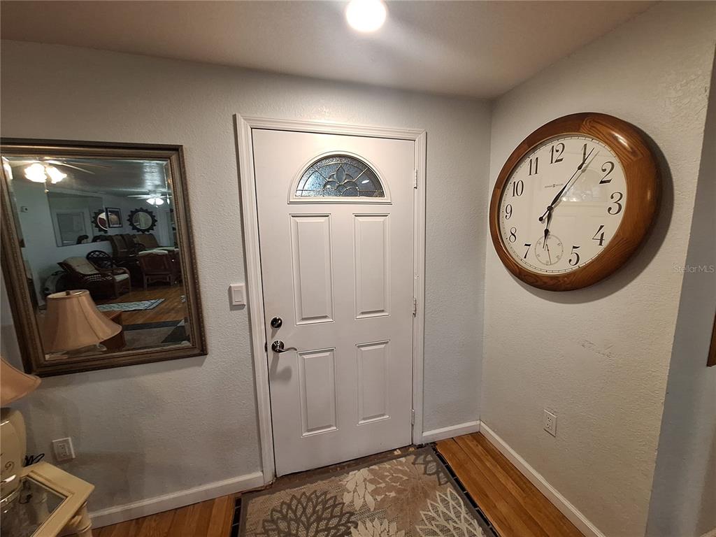 An entryway features a white front door, a large wall clock, and a decorative mirror — 4050 YUCATAN CIRCLE, PORT CHARLOTTE, FL