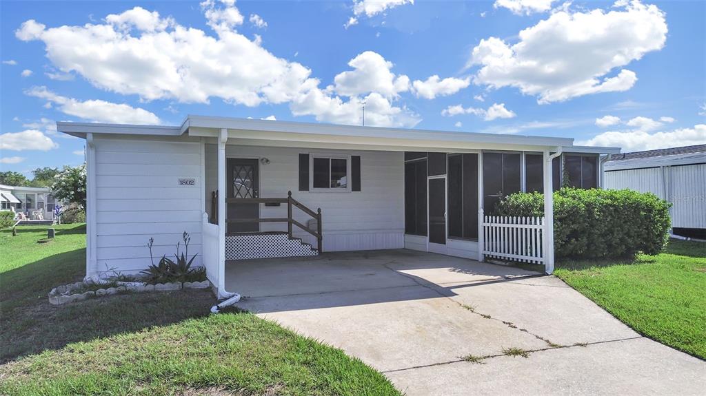 A white single-story manufactured home features a concrete driveway, a carport, and a screened porch — 1802 SHERWOOD HILL DR, LAKELAND, FL