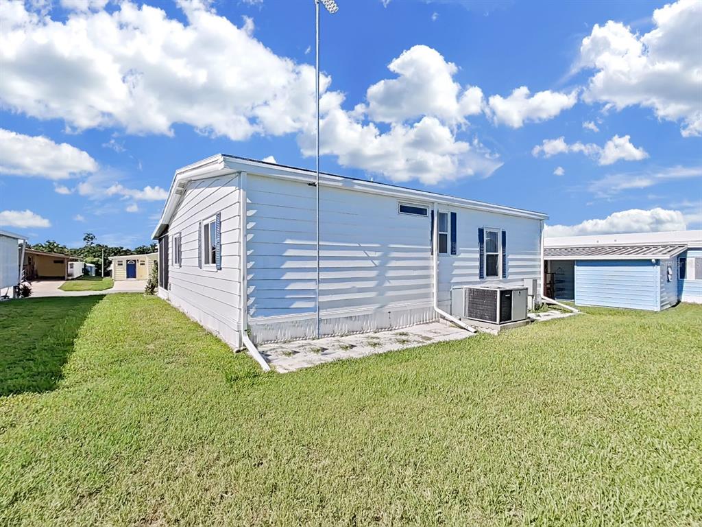 The exterior of a white mobile home features horizontal siding, a metal antenna, and an AC unit — 1802 SHERWOOD HILL DR, LAKELAND, FL