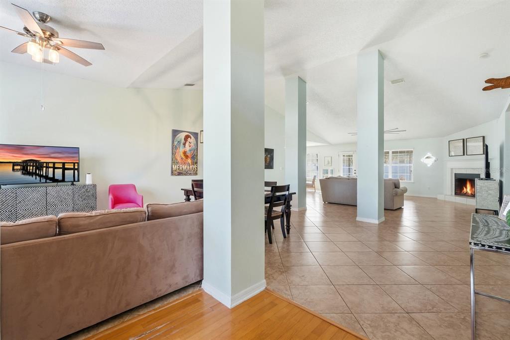 A spacious living area features tile and wood flooring, support columns, and a fireplace — 14 ROXANNE LANE, PALM COAST, FL