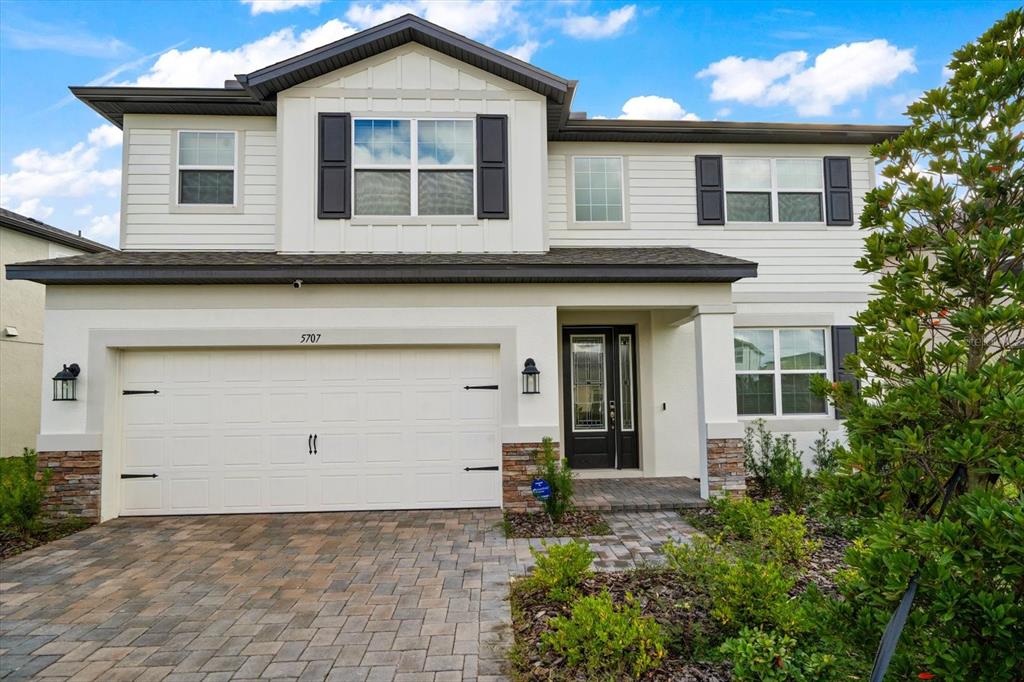 A two-story house with a white facade, stone accents, and a paved driveway — 5707 MAYDALE AVENUE, WESLEY CHAPEL, FL