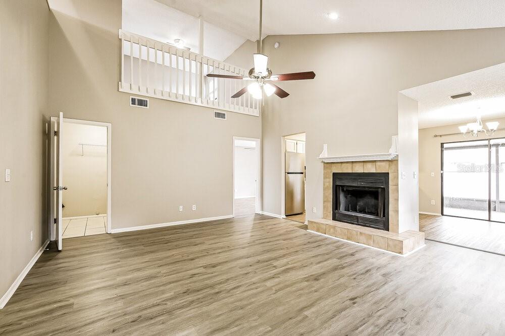 A living room features wood-look flooring, a fireplace, a ceiling fan, and a loft overlook — 1226 CREEKBOTTOM CIRCLE, ORLANDO, FL
