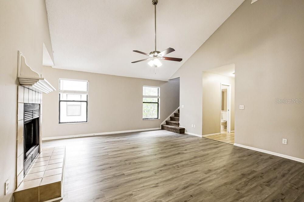 A living room with a vaulted ceiling, fireplace, ceiling fan, and wood-look flooring — 1226 CREEKBOTTOM CIRCLE, ORLANDO, FL